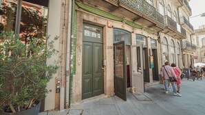 A building with a green door, a balcony with metal railings, and a potted plant. - Flores Deluxe by Hosty (Porto)