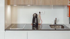 A kitchen with a coffee maker, a sink, and wooden cabinets. - Flores Deluxe by Hosty (Porto)