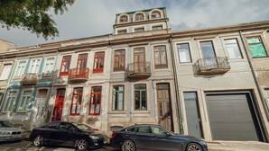A row of multi-story buildings with balconies, a cobblestone street, and parked cars. - Bonfim Vintage by Hosty (Porto)