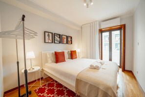 A hotel room with a large bed, a standing lamp, a red patterned rug, and artwork on the wall. - Bonfim Vintage by Hosty (Porto)