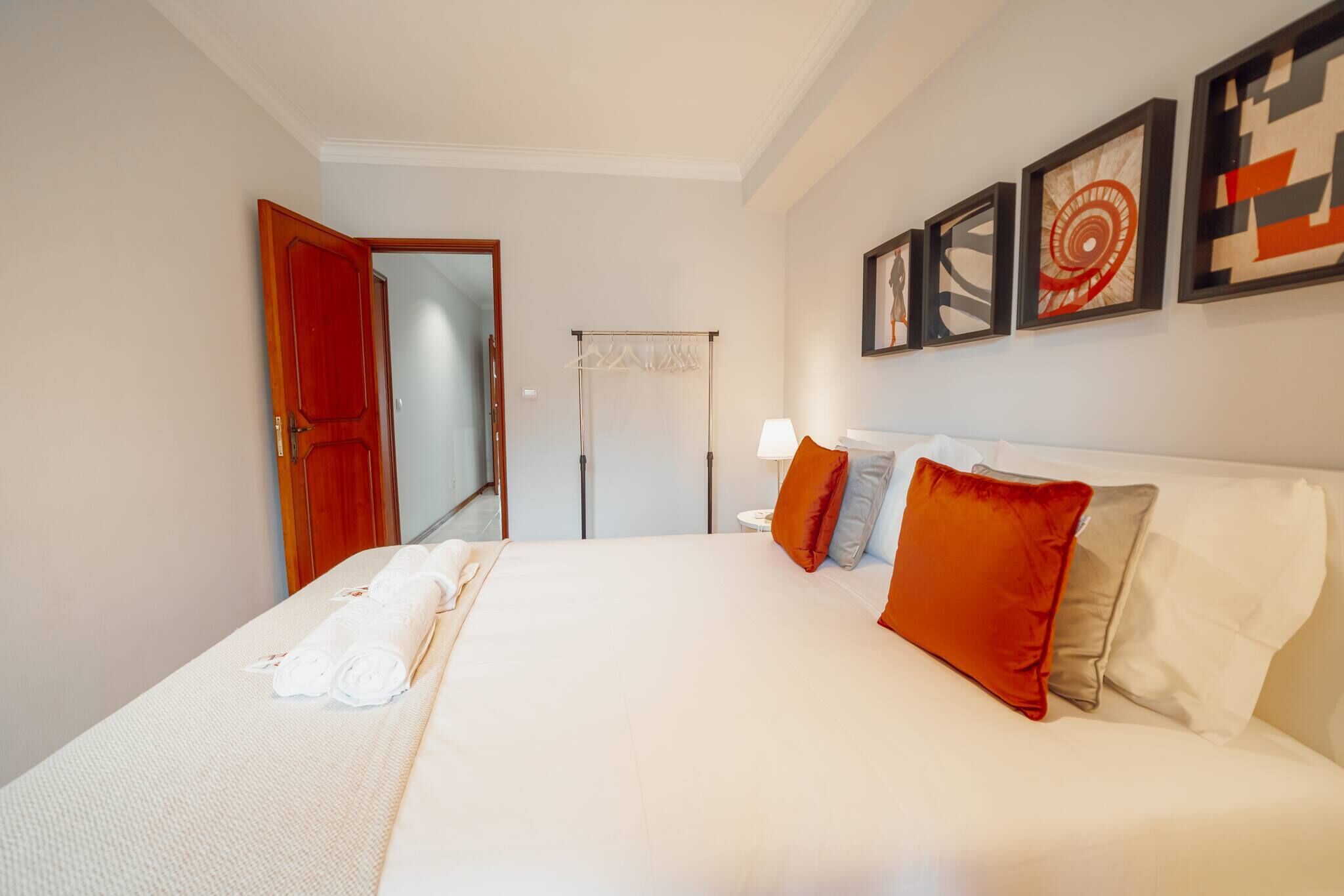 A hotel room with a large bed, a wardrobe, a mirror, and artwork on the wall.