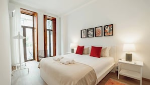 A bedroom with a bed, bedside tables, a window, and artwork on the wall.