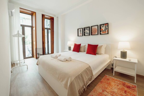 A bedroom with a bed, bedside tables, a window, and artwork on the wall.