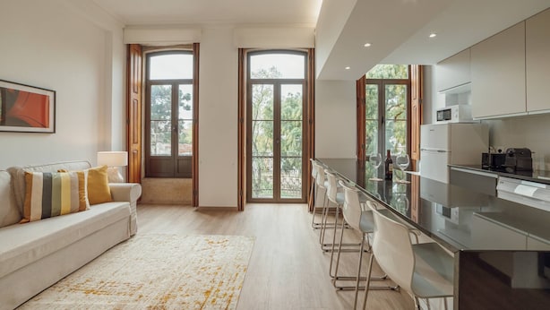A modern kitchen with a bar area, large windows, and a sofa with striped pillows.