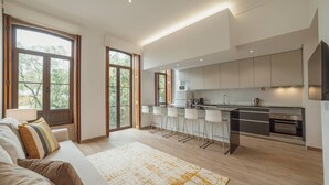 A modern kitchen with a central island, bar stools, and a dining area.