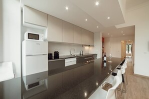 Uma cozinha moderna com uma ilha central, eletrodomésticos embutidos e um espaço de refeições com banquetas.
