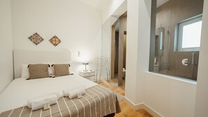 Een moderne hotelkamer met een groot bed, een nachtkastje met lamp, een glazen douchecabine en uitzicht.