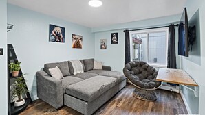 Een moderne woonkamer met een grijze bank, een ronde fauteuil en een kleine houten tafel.