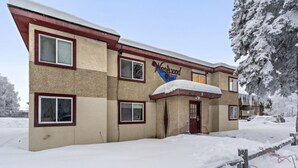 Een gebouw met twee verdiepingen, met een bord waarop 'Neskwood Inn' staat. Het heeft meerdere ramen en een sneeuwbedekte kap.