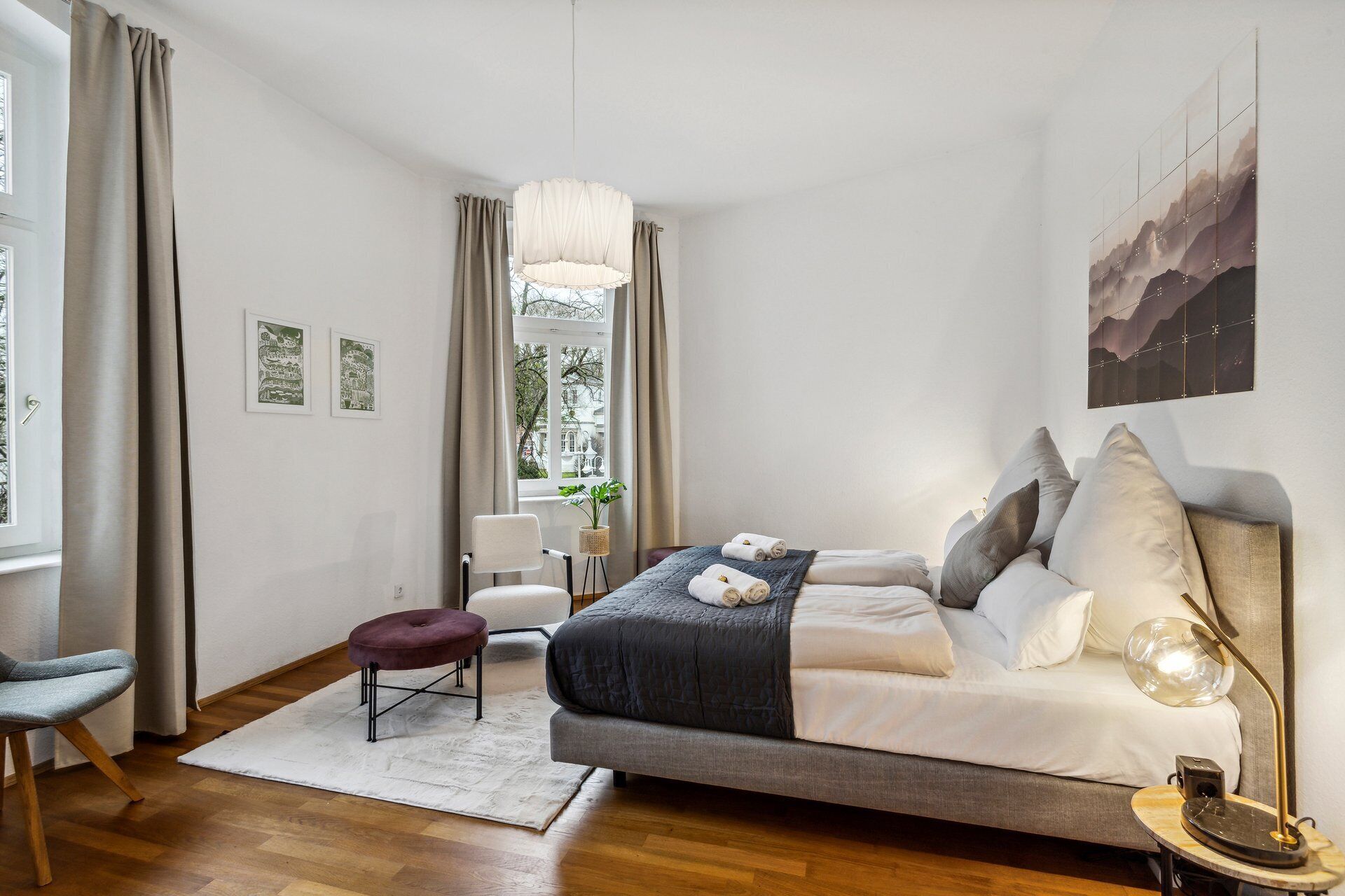A modern bedroom with a bed, a desk, a chair, and a window with curtains.