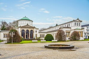 A classical building with a central dome, symmetrical windows, and a circular fountain in the courtyard.