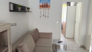 A modern living room with a beige sofa, a small white table, and a TV on a shelf. - Panorama 180° (Unknown)
