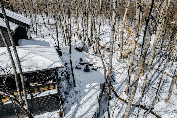 A cabin with a snow-covered roof, surrounded by a forest.