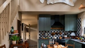A kitchen with a central island, green cabinets, and a hanging pot rack.