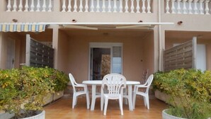 A covered outdoor patio with a white table and chairs, surrounded by potted plants. - T2 GOLFE DE LAVA BORD DE MER AVEC PISCINE (Appietto)