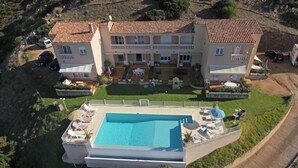 A large two-story building with a swimming pool, surrounded by greenery and a hilly landscape. - T2 GOLFE DE LAVA BORD DE MER AVEC PISCINE (Appietto)