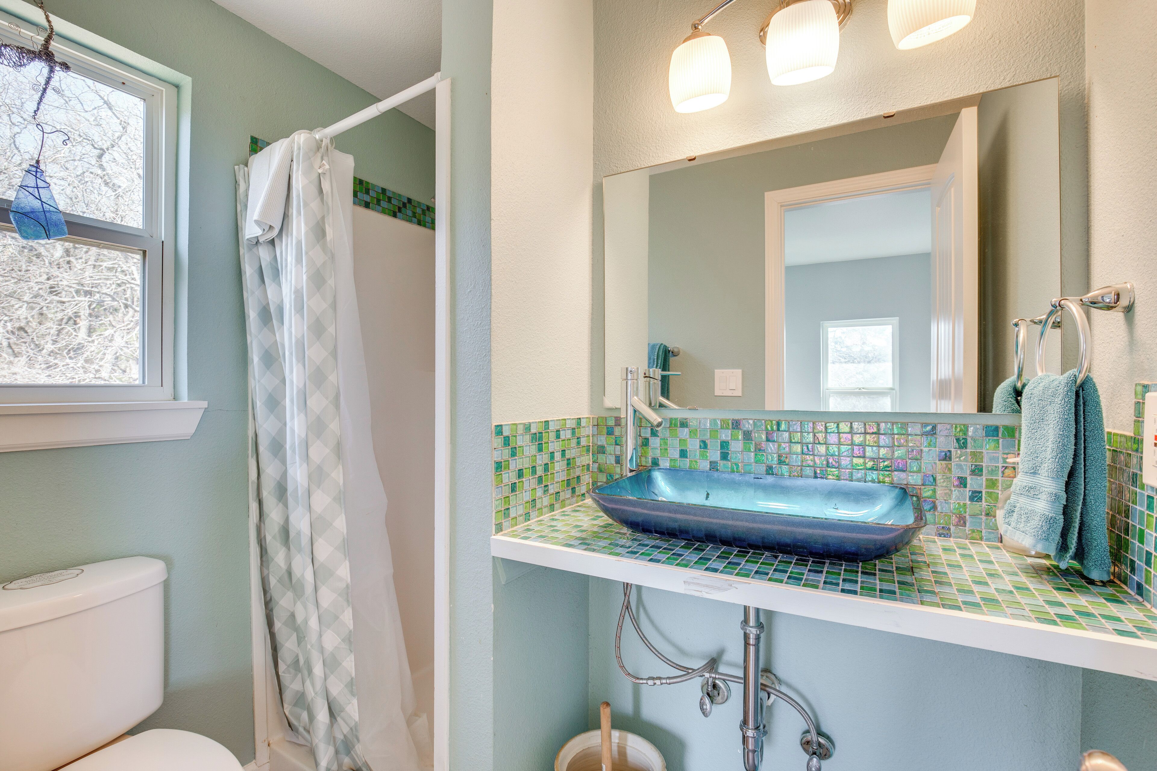 A bathroom with a white toilet, a blue sink, and a shower curtain.
