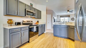 A modern kitchen with grey cabinets, stainless steel appliances, and a wooden floor. - 11 Mi to Disney: Home w/ Pool in Davenport! (Davenport)