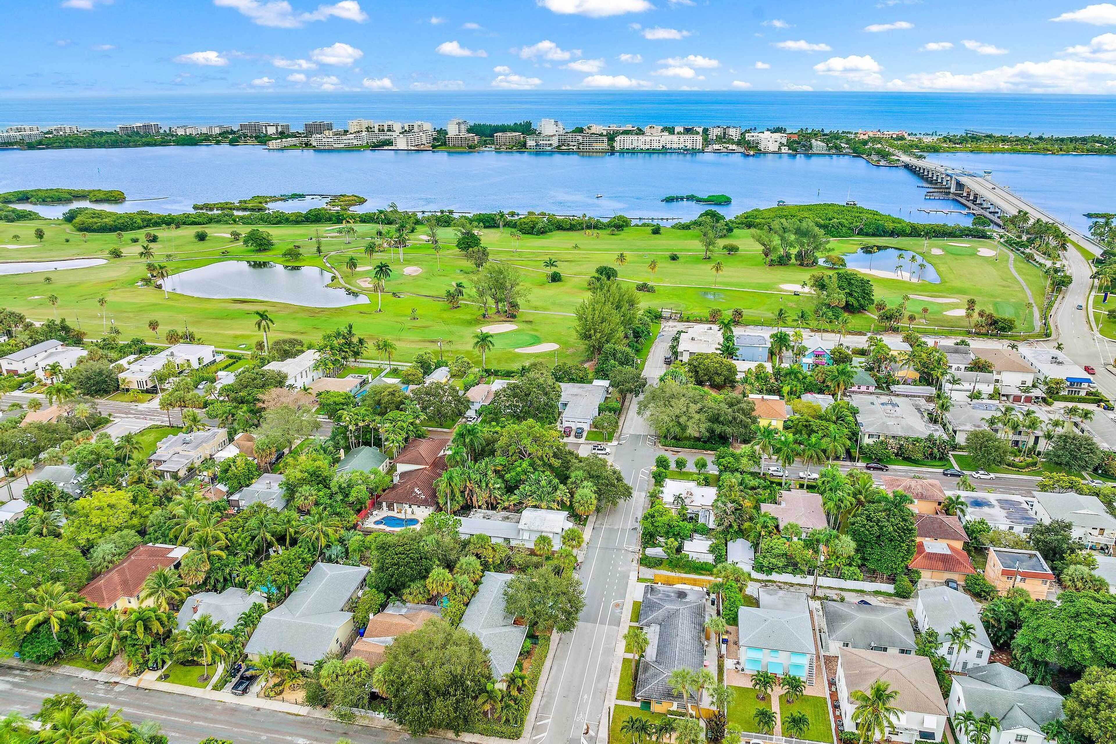 An aerial view of a coastal residential area with houses, a golf course, and a marina.