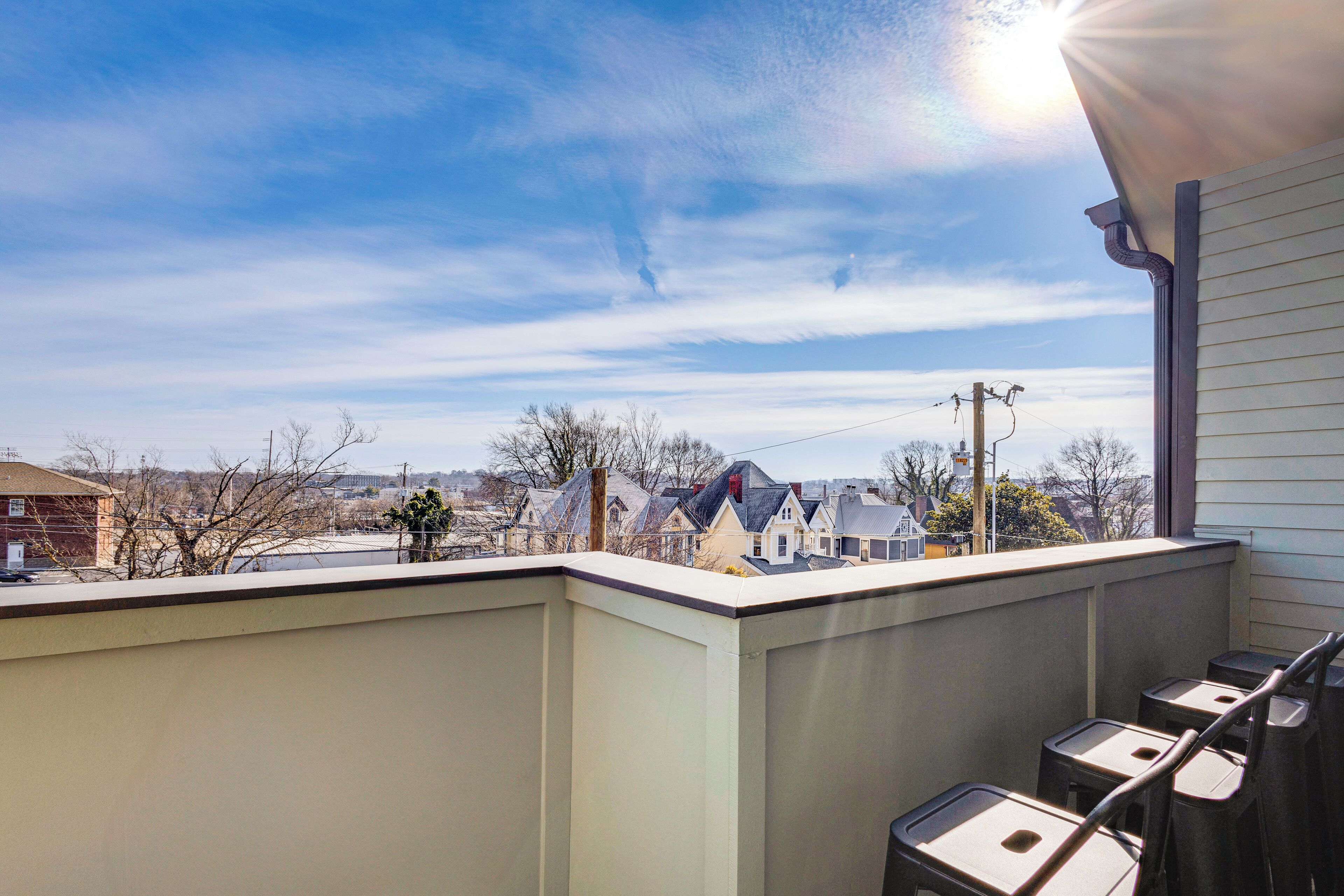 Un balcon donnant sur un quartier, avec vue sur les maisons et les lignes électriques.