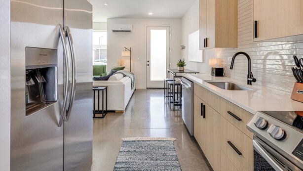 Une cuisine moderne dotée d’appareils électroménagers en acier inoxydable, de meubles en bois et d’un îlot central avec des tabourets de bar.