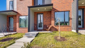 Un bâtiment moderne à deux étages, doté d’une façade en briques, de grandes fenêtres et d’un petit espace porche avec une chaise.