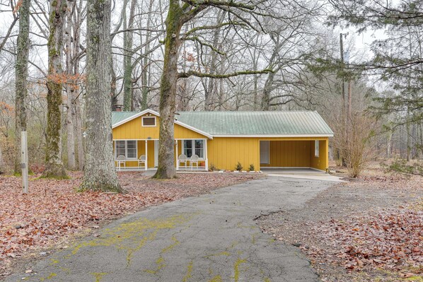 A yellow building with a green roof, surrounded by trees and a gravel driveway. - Deck & 2-acre Yard: Quiet Getaway in Crandall! (Crandall)