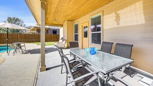 An outdoor patio with a glass table and chairs, a wooden ceiling, and a view of a swimming pool. - 5 Mi to Randolph Afb: Spacious Cibolo Haven! (Cibolo)