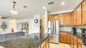 A modern kitchen with granite countertops, stainless steel appliances, wooden cabinets, and a large island. - 5 Mi to Randolph Afb: Spacious Cibolo Haven! (Cibolo)
