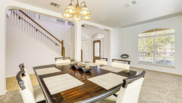 A dining area with a large wooden table, white chairs, and a chandelier. - 5 Mi to Randolph Afb: Spacious Cibolo Haven! (Cibolo)