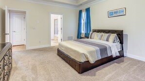 Une chambre à coucher avec un grand lit, une commode et un ventilateur de plafond.
