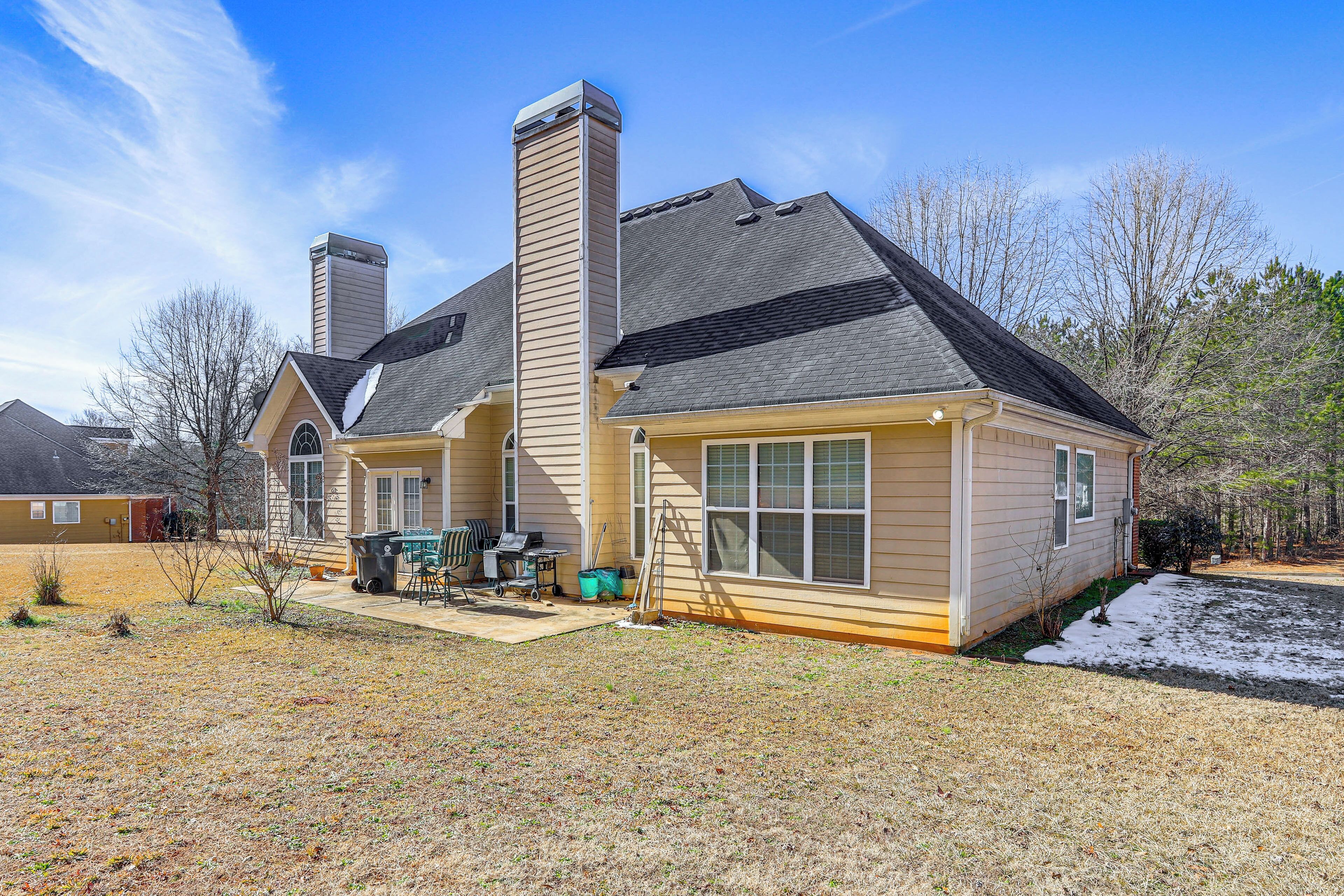 A two-story house with a chimney, a garage, and a small front yard with a snow patch.