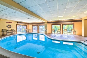 Une piscine intérieure équipée d’une horloge, de chaises et d’un panneau indiquant qu’il est interdit de sauter ou de plonger.