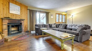 Un salon avec une cheminée, un canapé d’angle, une table basse et une lampe.