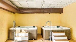 Une salle de spa équipée de deux bains à remous, d’un escalier en bois et d’une bouche d’aération au plafond.