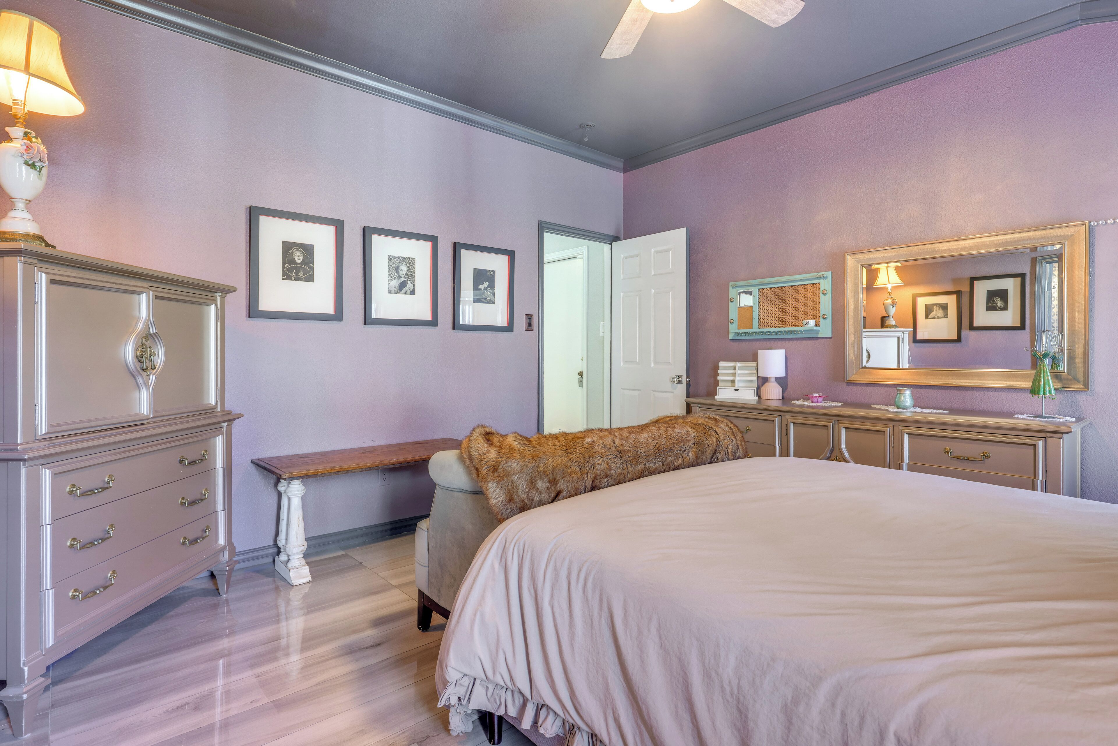 Une chambre à coucher avec un grand lit, une commode, un banc et une porte.