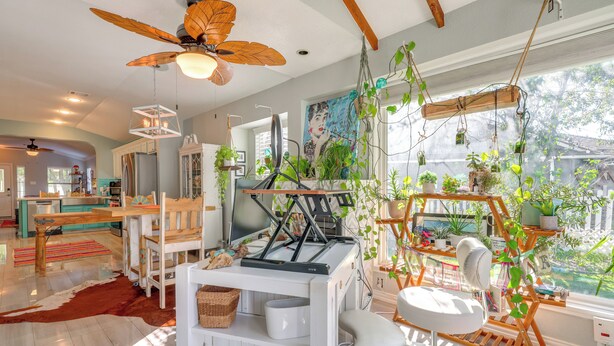 Et moderne køkken med spiseplads, ventilator i træloft og forskellige planter.