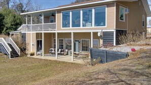 Een tweelaags huis met een balkon, een overdekte patio en een trap naar de bovenverdieping.