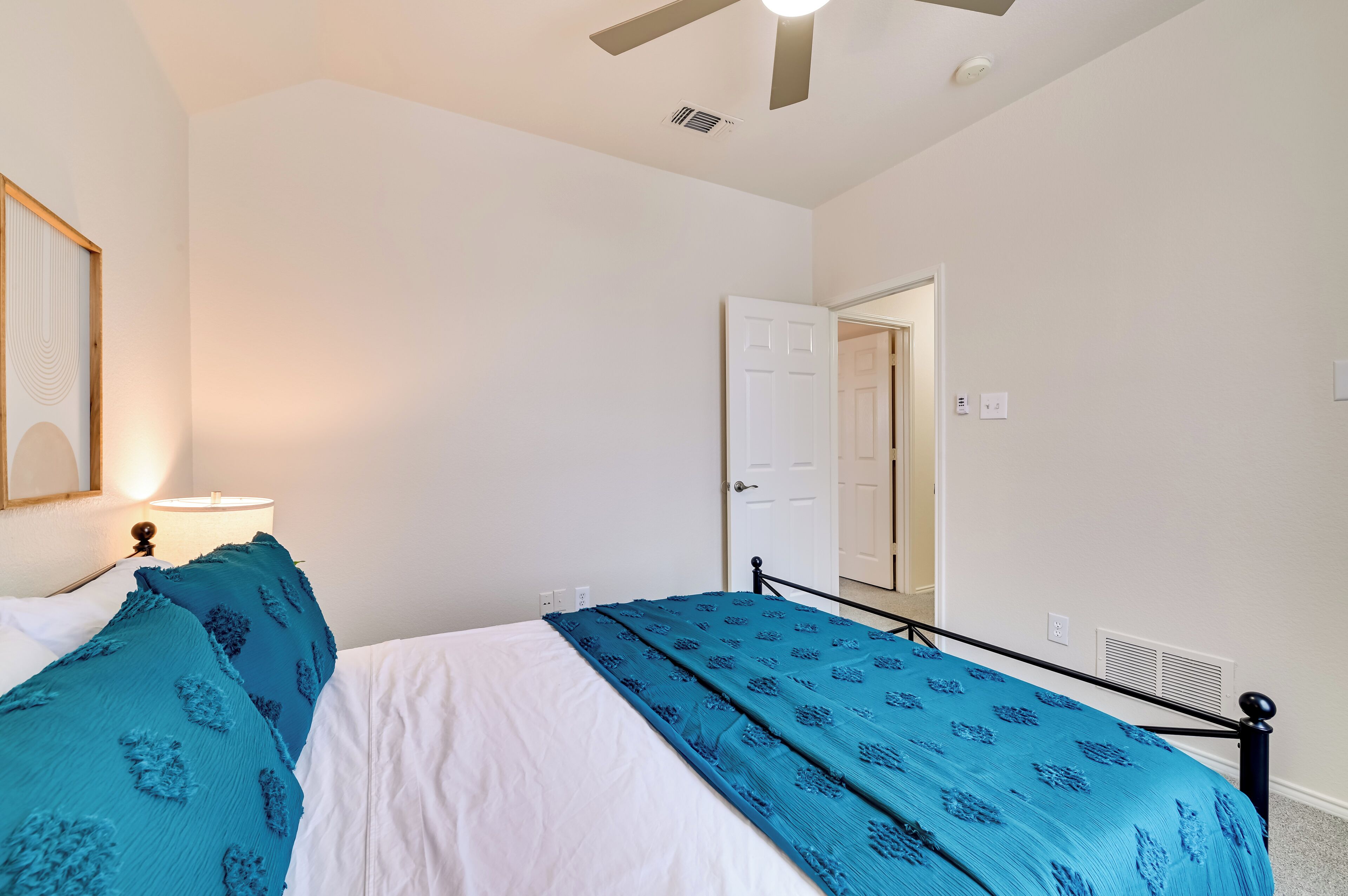 Ein Schlafzimmer mit Bett, Deckenventilator, Tür und einer Wandleuchte.