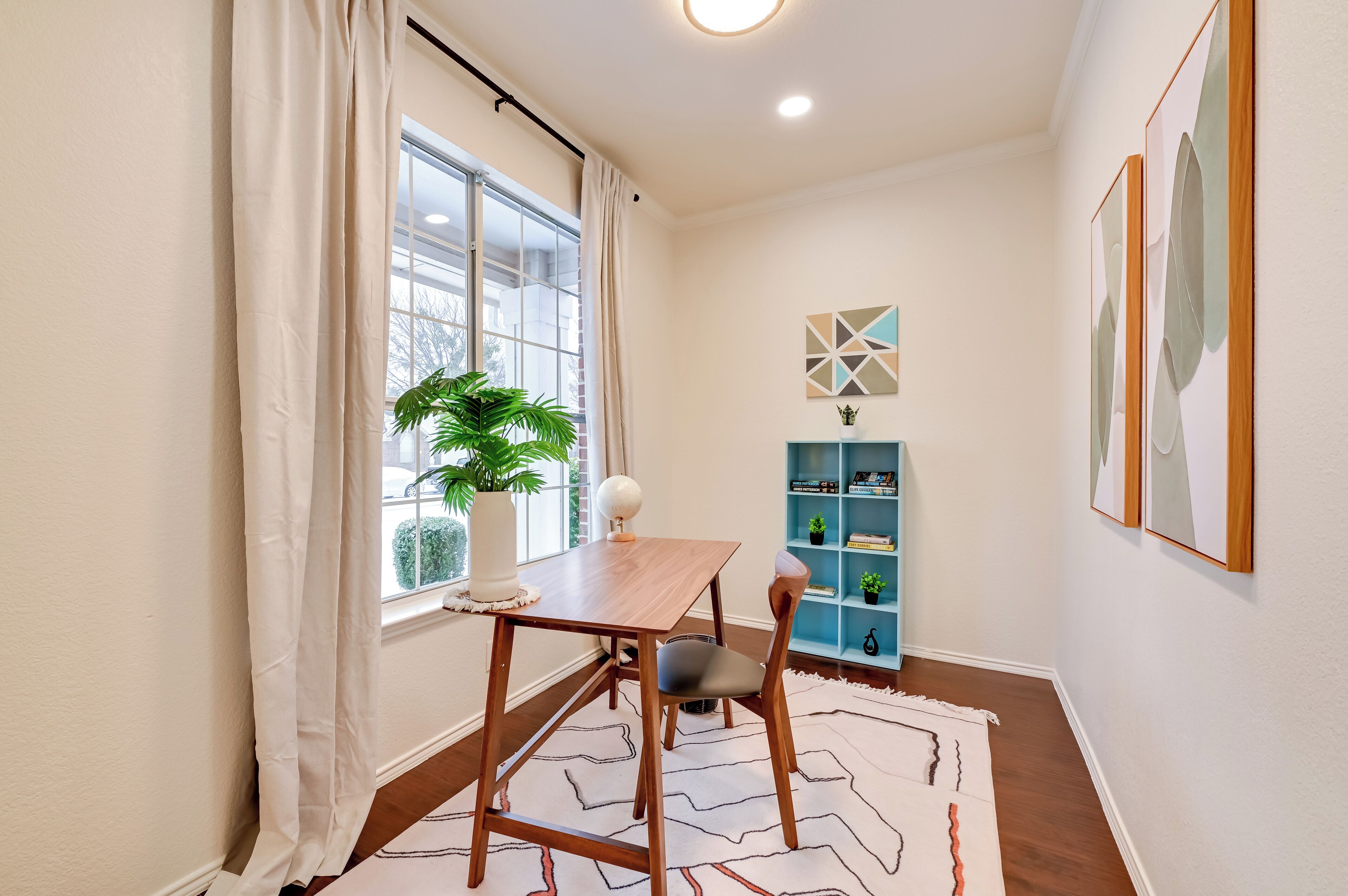 Un comedor con una mesa y sillas de madera, una planta en maceta y un estante azul con objetos decorativos.