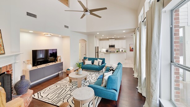 A spacious living room with a large flat-screen TV, teal sofas, a fireplace, and a kitchen in the background. - 4 Mi to Dtwn: Family Home w/ Games in Frisco (Frisco)