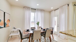 A dining area with a wooden table, six chairs, a vase with a plant, and a white chair with a small table. - 4 Mi to Dtwn: Family Home w/ Games in Frisco (Frisco)