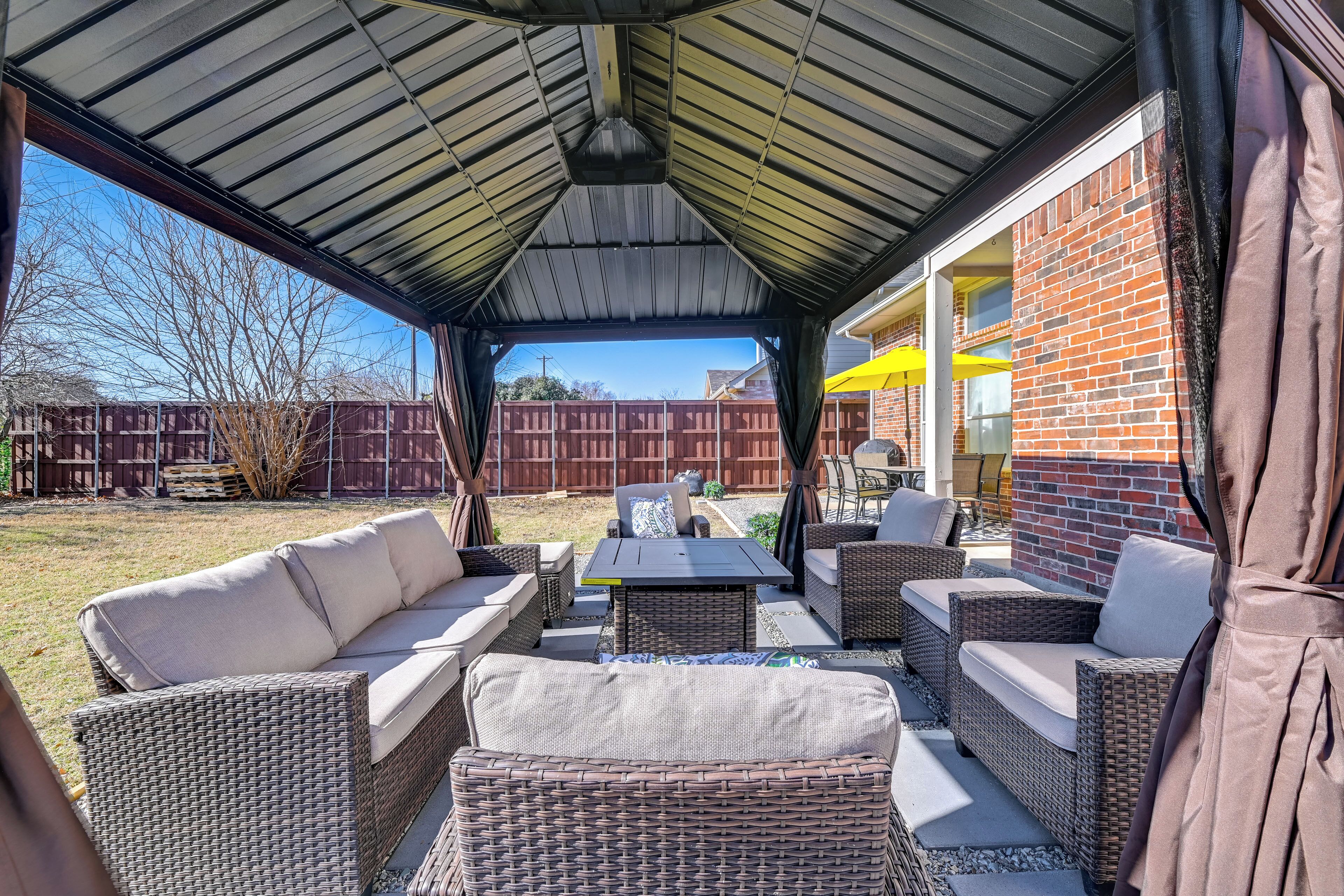 An outdoor patio with wicker furniture, a covered area, and a brick wall.
