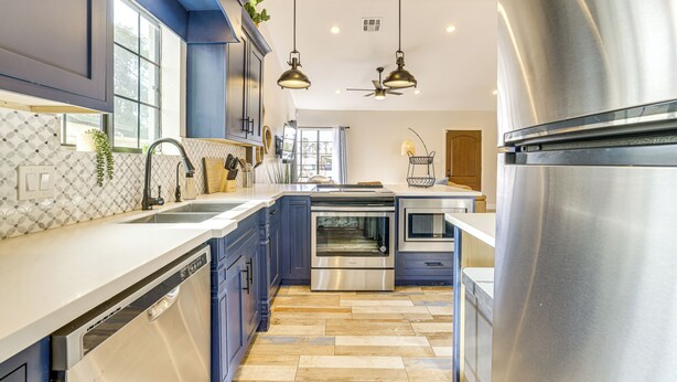 A modern kitchen with stainless steel appliances, blue cabinets, and a dishwasher. - 1 Mi to Grand Ave: Modern Home w/ Spacious Yard! (Phoenix)