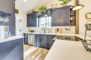 A modern kitchen with dark cabinets, a white countertop, and a wooden floor. - 1 Mi to Grand Ave: Modern Home w/ Spacious Yard! (Phoenix)
