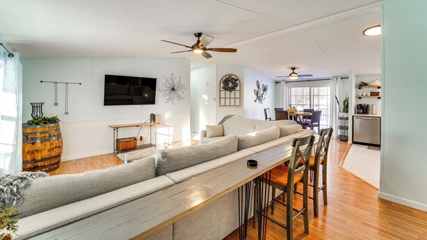 A modern living room with a long grey sofa, a wooden coffee table, and a ceiling fan. - Walk to Lakemont Park: Family-friendly Home! (Altoona)