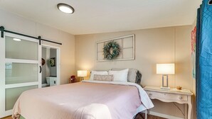 A bedroom with a bed, bedside lamps, a dresser, a wardrobe, and a wall-mounted wreath. - Walk to Lakemont Park: Family-friendly Home! (Altoona)