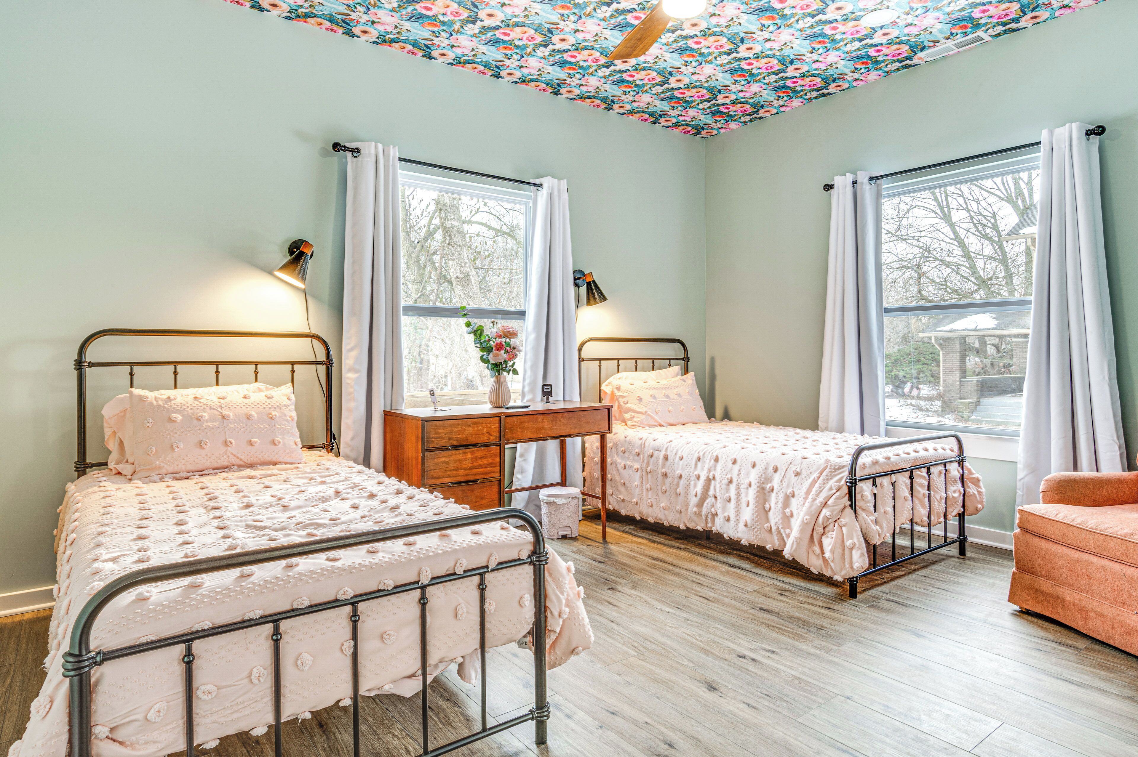 A bedroom with two beds, a desk, and a chair.