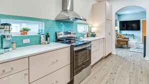 A modern kitchen with a stainless steel range hood, a built-in oven, and a countertop with a coffee maker and a plant.