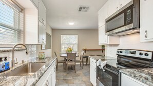A kitchen with white cabinets, a stainless steel sink, a built-in microwave, and a stove. - 5 Mi to Fort Worth Stockyards: Home w/ Yard! (Haltom City)